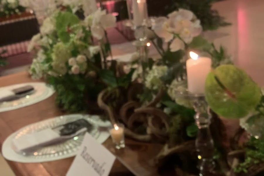 Mesa de evento decorada com arranjos de flores e velas