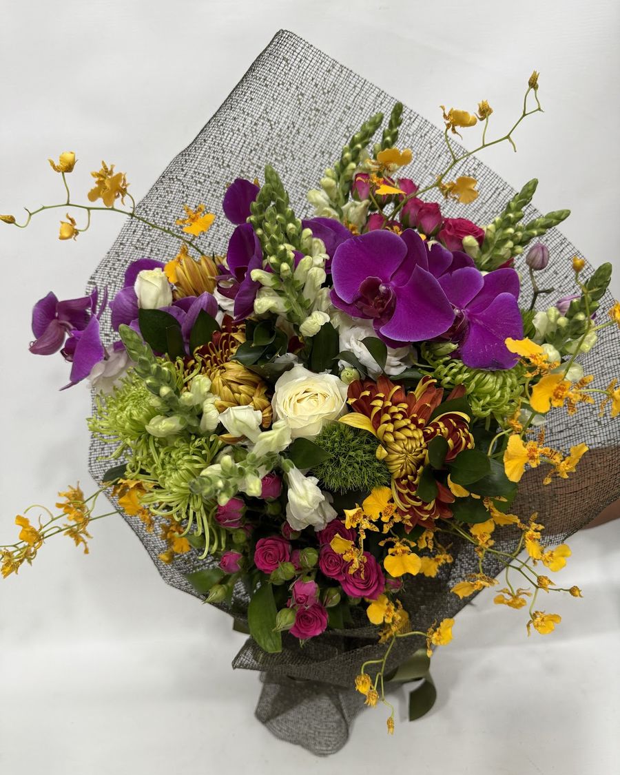 Bouquet colorido com orquídeas roxas, rosas e flores amarelas, embrulhado pela Florear